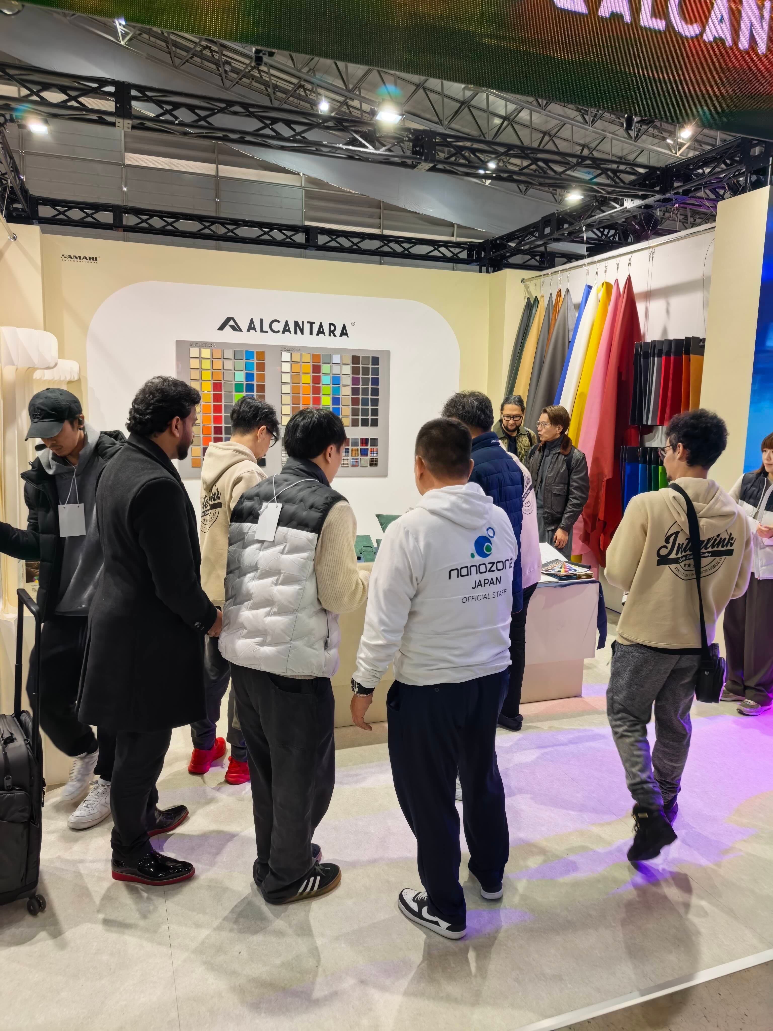 Visitors exploring materials and speaking with the CAMARI team at Tokyo Auto Salon